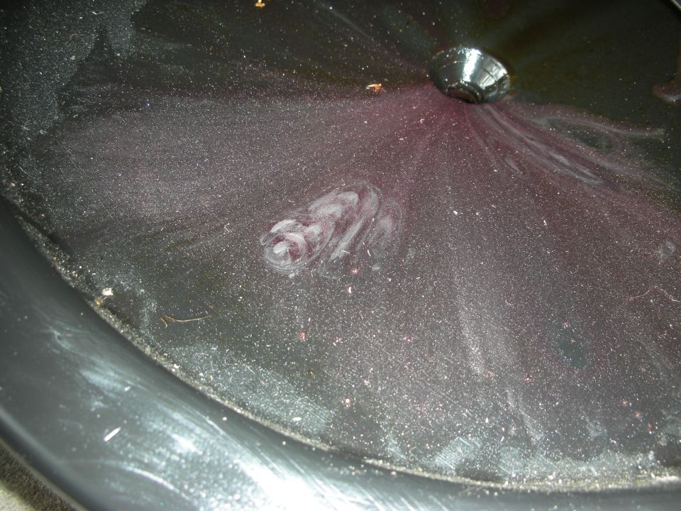 Dark transmission pan with purple fluid residue and swirl marks