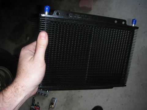 1992 Ford Crown Victoria - A black transmission cooler with blue fittings is held up for inspection.