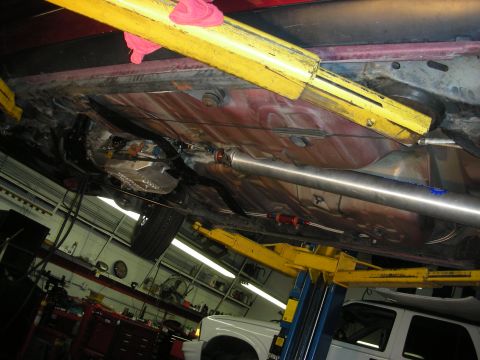 1992 Ford Crown Victoria - The underside of a vehicle is shown on a lift in a garage, with another vehicle partially visible in the background.