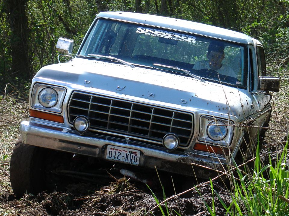 Silver 1978 Ford Bronco stuck in mud, front 3/4 view, with "SKYJACKER" sticker on windshield
