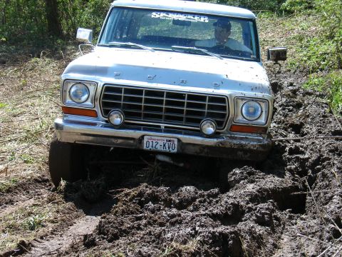 1978 Ford Bronco - This 1978 Ford Bronco is stuck deep in a muddy trail, with its front grille and tires covered in mud.