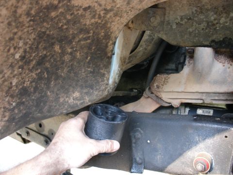 1978 Ford Bronco - A person is installing a body lift puck onto the frame of a vehicle, likely for suspension modification.