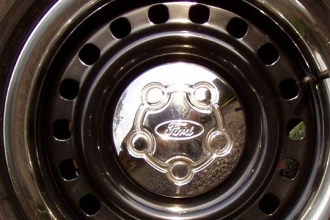 1999 Ford Crown Victoria - A chrome Ford hubcap with the Ford oval logo is shown on a vehicle's wheel.