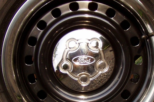 Close-up of a Ford hubcap on a dark wheel with several circular cutouts