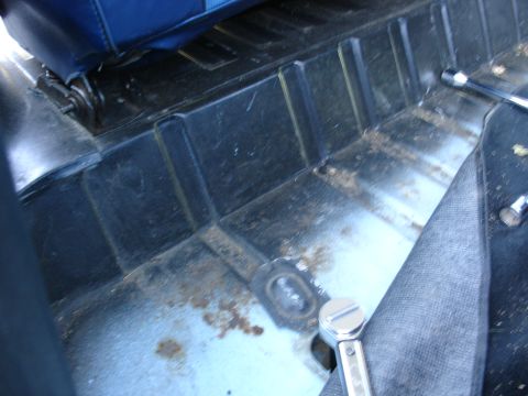 1978 Ford Bronco - The interior floor of a vehicle shows signs of wear and rust, with a socket wrench visible.