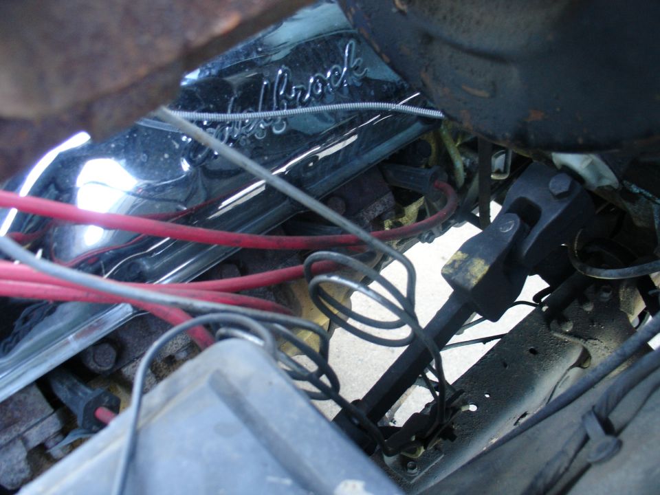 Chrome Edelbrock valve cover with red plug wires and steering shaft U-joint in engine bay
