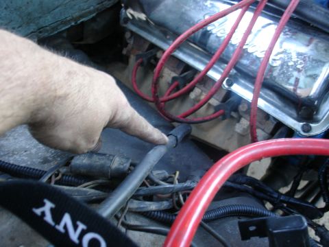 1978 Ford Bronco - Close-up view of a vehicle's engine bay, focusing on a hand pointing to a hose.