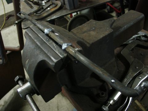 1978 Ford Bronco - A metal rod is secured in a vise, undergoing some modification with visible welds.