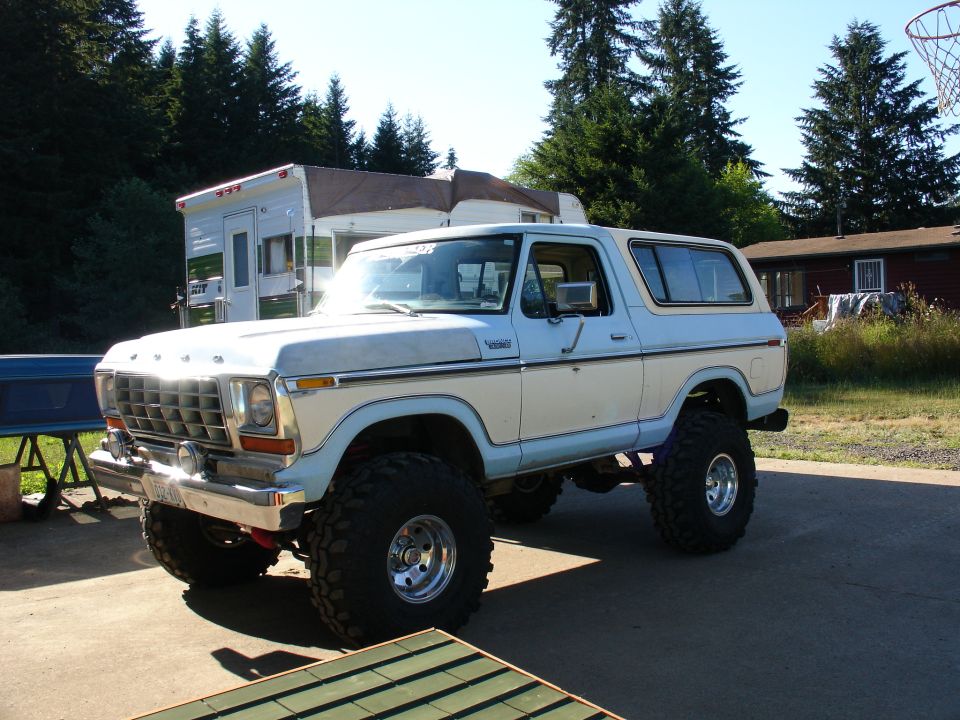 White lifted Ford Bronco on large tires parked in a gravel yard