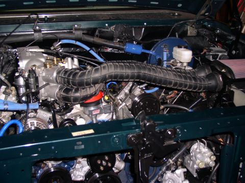 1993 Ford Bronco - Close-up view of a vehicle's engine bay, a prominent black air intake hose and various blue hoses.