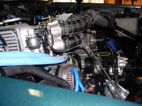 1993 Ford Bronco - Close-up of an engine bay aftermarket modifications and blue hoses.