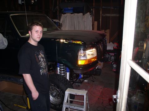 1993 Ford Bronco - A dark green Ford Bronco is parked indoors with its hood up, revealing the engine compartment.