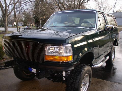 1993 Ford Bronco - This dark green Ford Bronco appears to be from the early to mid-1990s, with a prominent chrome grille and lifted suspension.