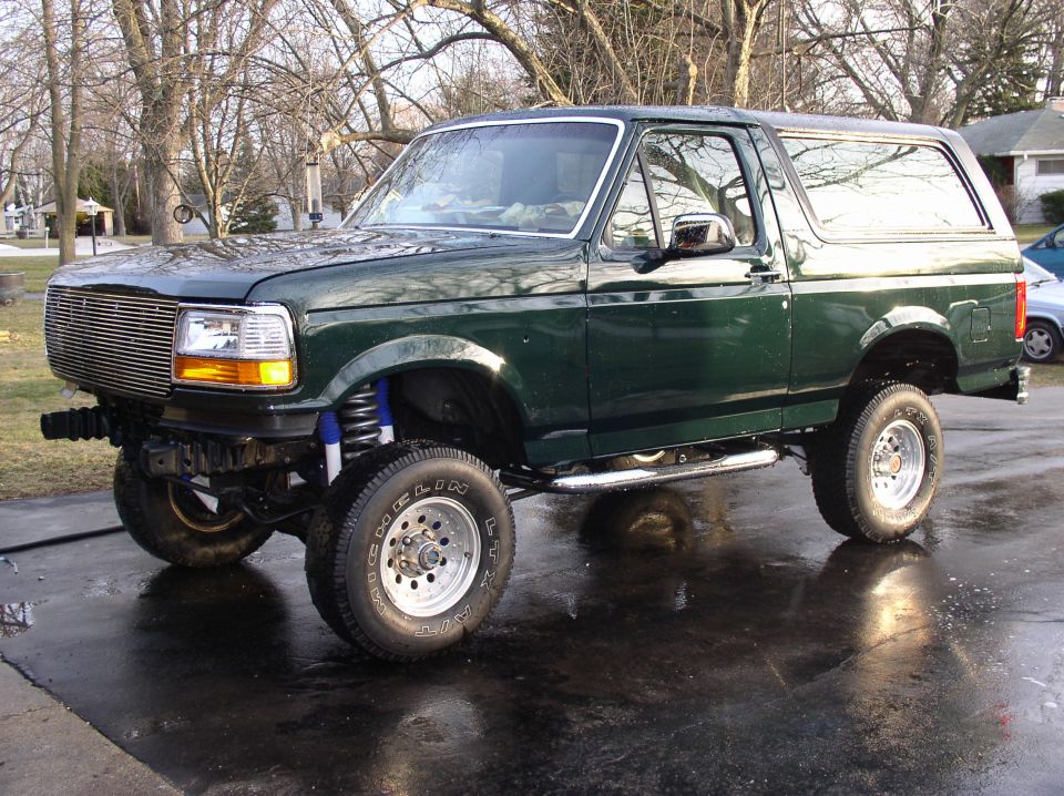 Green 1993 Ford Bronco 3/4 front view with lifted suspension and aftermarket grille