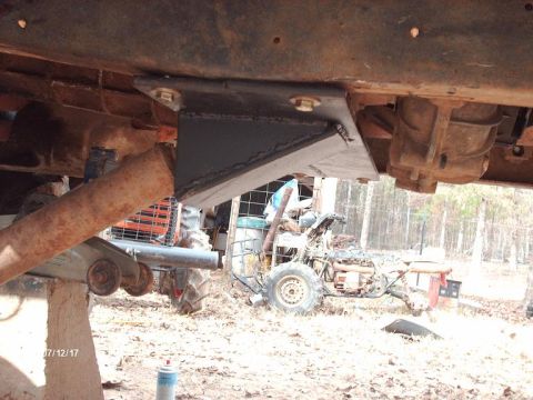 1990 Ford F-150 - Underside view of a custom-fabricated bracket installed on a vehicle's frame, with other vehicles in the background.