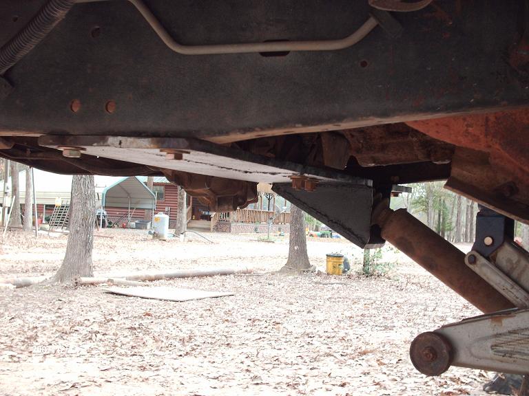 Underside of a 1990 Ford F-150 showing a straight axle swap modification with custom brackets and a shock absorber