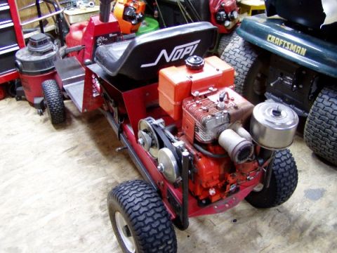 1999 Ford Crown Victoria - A custom red riding mower with an exposed engine sits beside a green Craftsman mower in a garage.