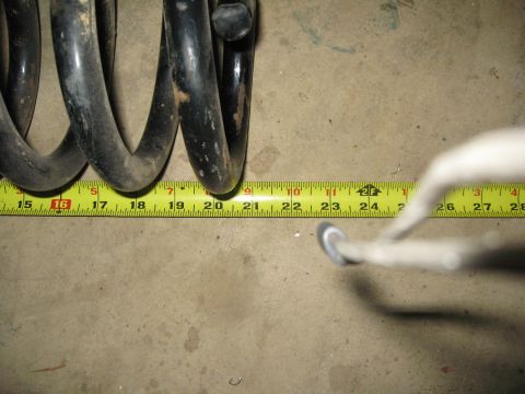 2007 Ford Bronco - A close-up shows a black coil spring being measured with a yellow tape measure on a concrete floor.