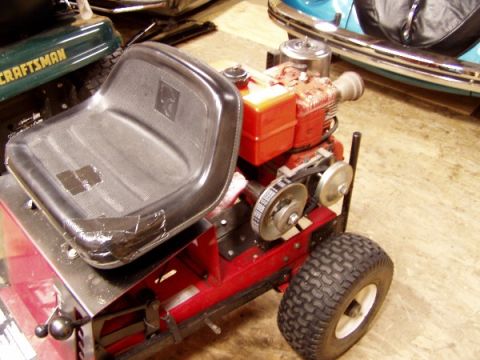1999 Ford Crown Victoria - A red lawn tractor's engine and seat are visible, with a green Craftsman mower in the background.