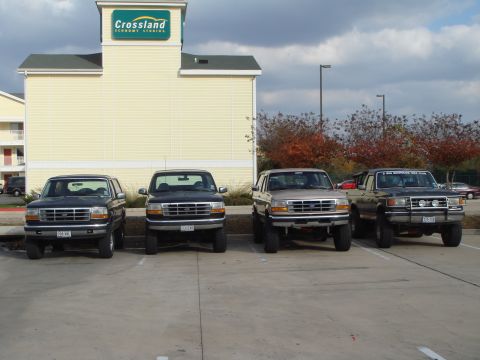 1992 Ford Bronco - Multiple Ford Broncos are parked in a lot outside a Crossland hotel.