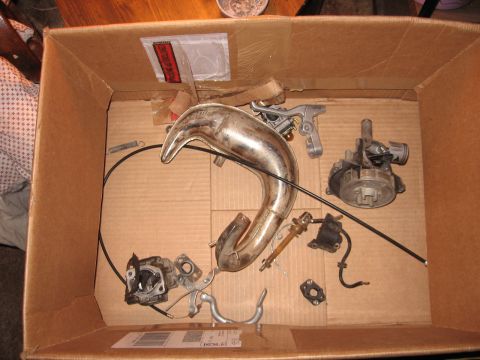 1992 Ford Crown Victoria - Various engine and exhaust components are laid out inside a cardboard box, suggesting a project or repair.