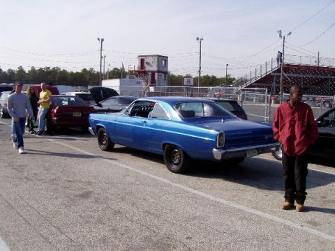 1999 Ford Crown Victoria - A blue 1966 Ford Fairlane coupe is parked at a drag strip with spectators in the background.