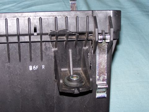 1995 Ford Probe - Close-up of a damaged black plastic automotive part with a metal bracket, showing some text and wear.