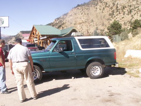 1986 Ford Bronco - This green Ford Bronco with a white top is seen from the side. The body style suggests it is from the early 1990s, not 1986 as claimed.