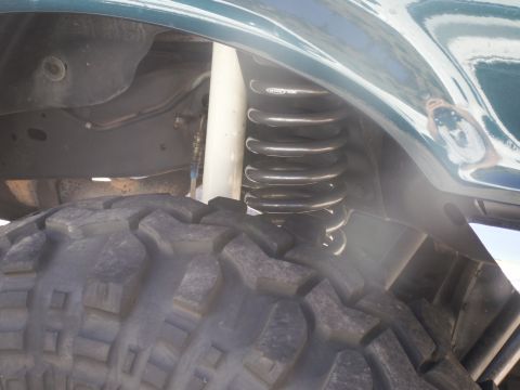 1986 Ford Bronco - Vehicle's suspension and tire detail, showing a large off-road tire and coil spring.