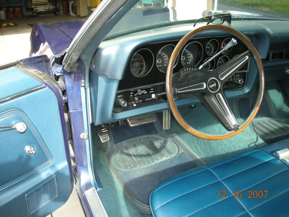 Interior of a 1970s Ford with wood-rim steering wheel and blue dash