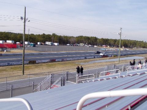 1999 Ford Crown Victoria - A drag strip scene with multiple vehicles and spectators under an overcast sky.