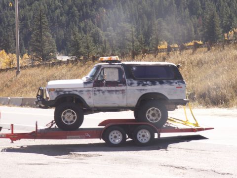 1986 Ford Bronco - A lifted Ford Bronco, weathered and worn, is transported on a trailer.