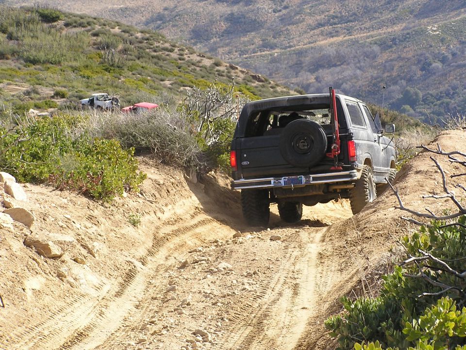 Gray Ford Bronco descending a deeply rutted dirt trail downhill