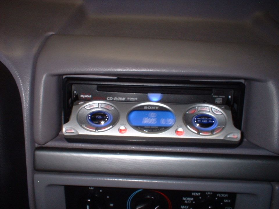 Sony CD-R/RW car head unit installed in gray dashboard with blue display lit