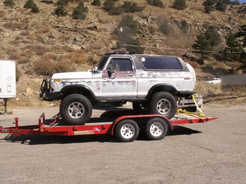 1986 Ford Bronco - A weathered Ford Bronco is loaded onto a trailer, ready for transport.