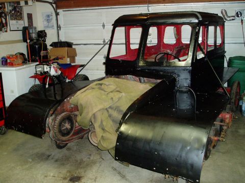 2000 Ford E350 - This custom vehicle appears to be a tracked machine with a cab, parked next to an ATV in a garage.
