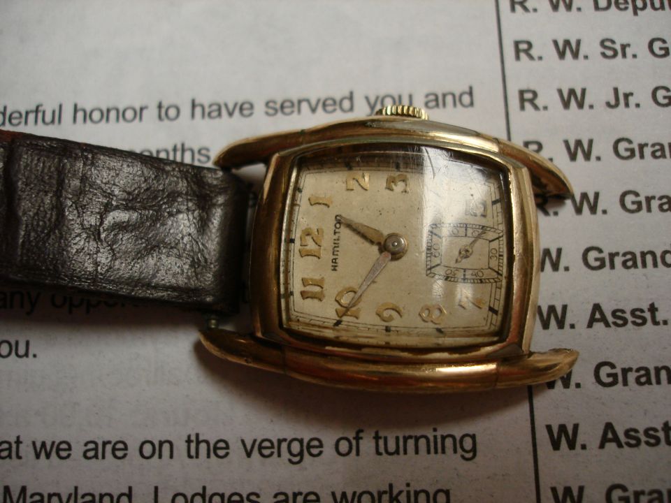 Gold-toned Hamilton watch with a black leather strap, face showing Arabic numerals and a subdial