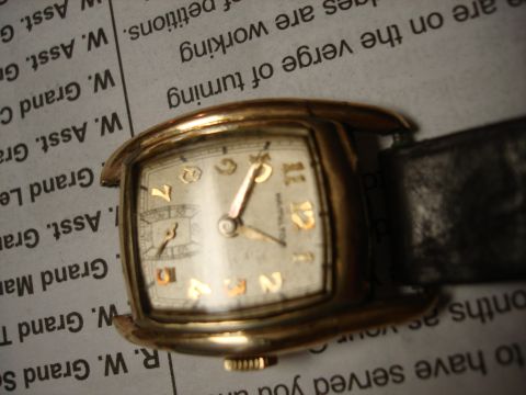 1994 Ford Bronco - A gold-toned watch with a black leather band rests on a page of text from a newspaper.