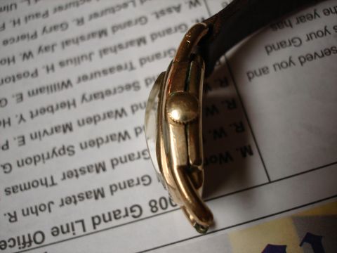 1994 Ford Bronco - A gold watch with a leather strap is shown resting on a printed document with text.