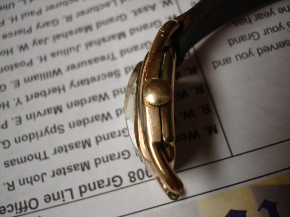 Close-up of a gold watch with a leather band, resting on a document