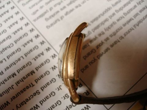 1994 Ford Bronco - A close-up side view of a watch with a cracked crystal, resting on a document with printed text.