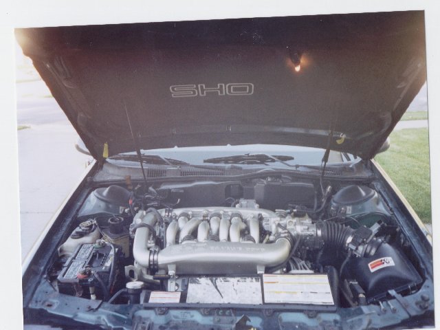 Open hood of a Ford Taurus SHO showing the V6 engine with silver intake manifold and aftermarket cone air filter