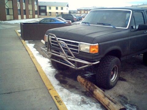 1990 Ford Bronco - This black 1990 Ford Bronco features a custom front bumper and is parked on a snowy lot.