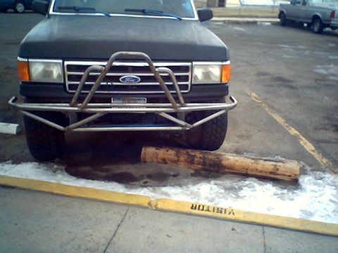 1990 Ford Bronco - Front view of a 1990 Ford Bronco with a custom bumper, parked over a log.