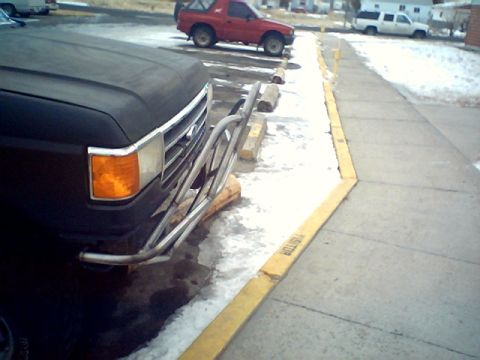 1990 Ford Bronco - A black pickup truck is parked in front of a red SUV and a white truck on a snowy day.