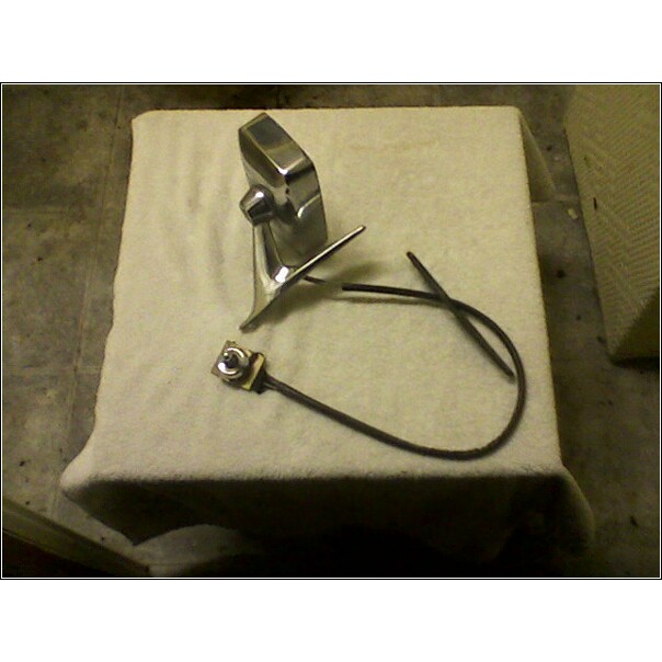 Chrome car door handle with black cable and mounting hardware on a white cloth