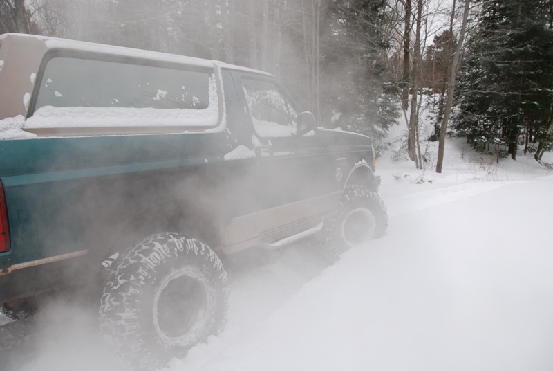 Teal and tan 1996 Ford Bronco in snow, rear 3/4 view