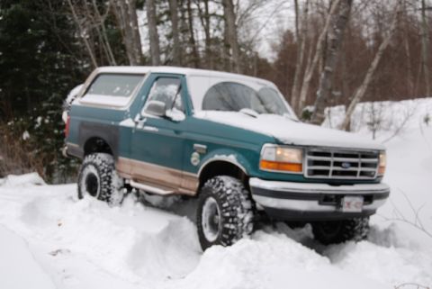 1996 Ford Bronco - 1996 Ford Bronco navigating a snowy, wooded area.