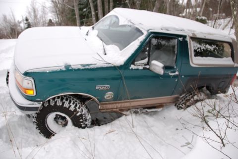 1996 Ford Bronco - A green 1996 Ford Bronco is stuck in deep snow, partially buried.