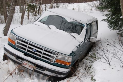 1996 Ford Bronco - A 1996 Ford Bronco is partially buried in snow, stuck off the side of a wooded area.